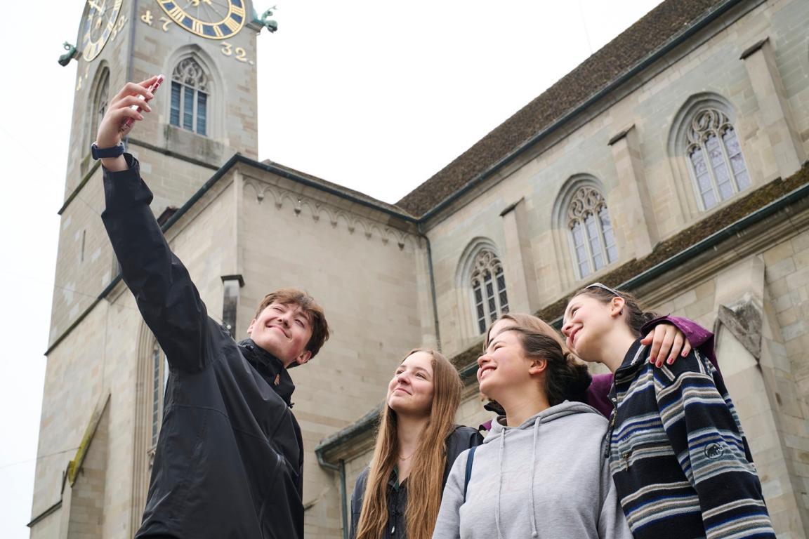 Vier Jugendliche lächeln in die Kamera eines Telefons für ein Selfie. 