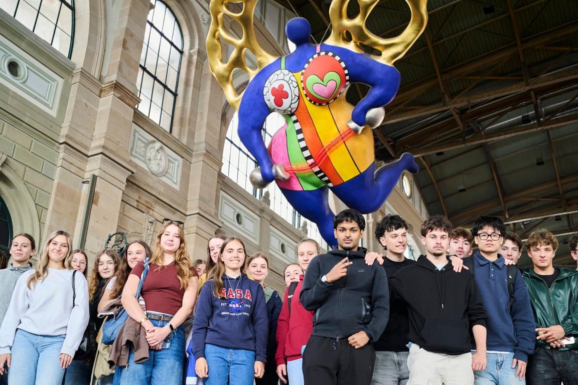 Eine Gruppe von Jugendlichen steht im Hauptbahnhof und schaut zur Kamera. 
