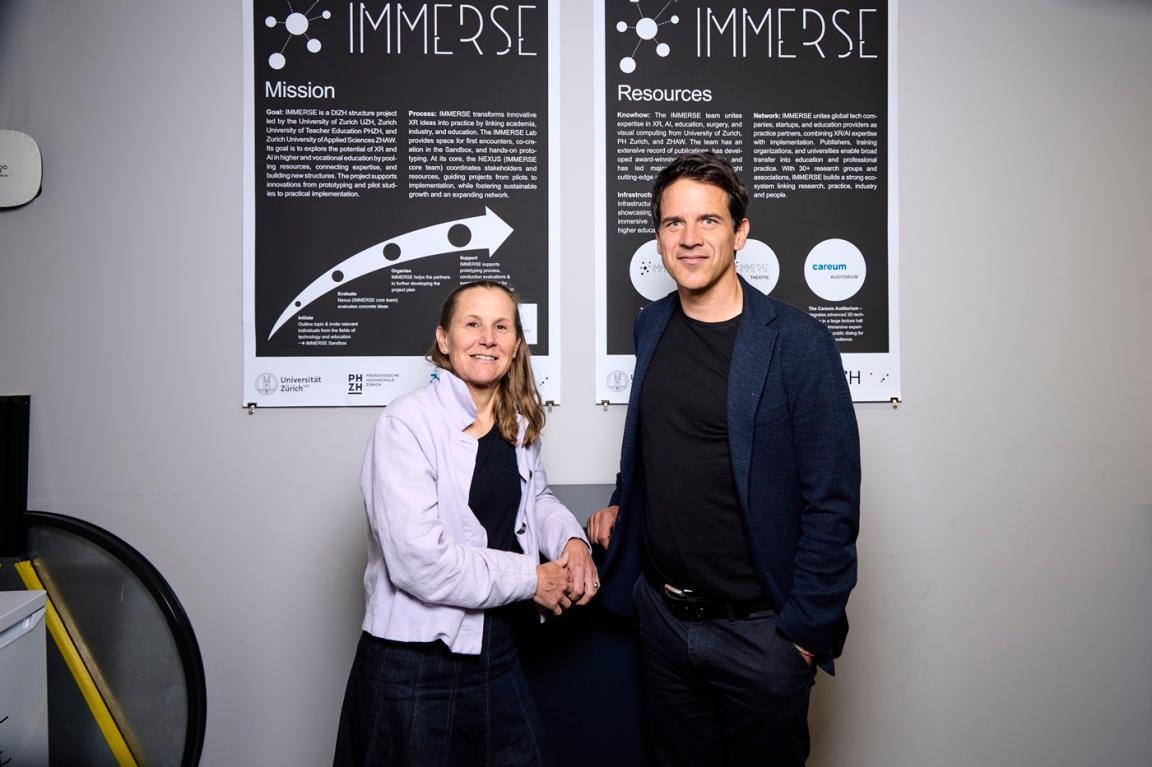 Simone Herzog und Martin Berger stehen vor einem Plakat.