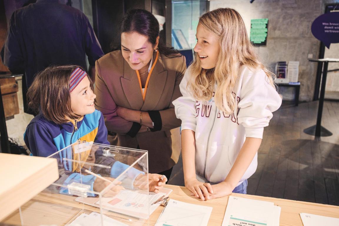 Zwei Schülerinnen unterhalten sich mit einer Lehreperson-