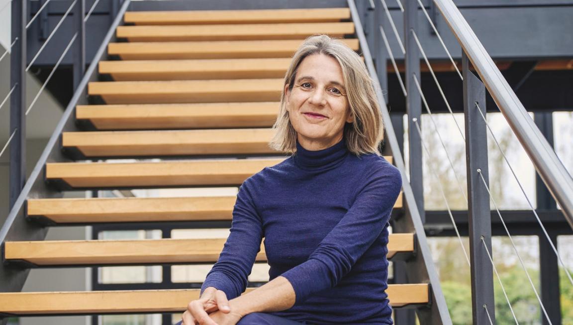 Eine Frau sitze auf einer hölzernen Treppe, die Hände auf den Knien abgestützt.