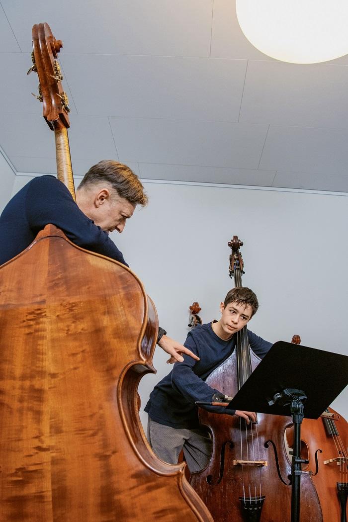 Der Kontrabass-Lehrer zeigt seinem Schüler etwas auf den Noten.