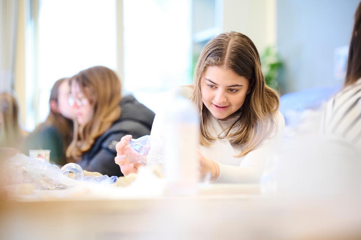 Schülerinnen sitzen im Klassenzimmer und betrachten Plastikabfall.