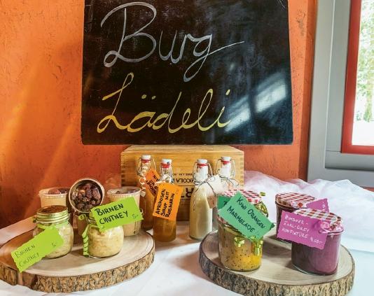 Auf zwei rustikalen Brättli werden kulinarische Spezialitäten präsentiert. Im Hintergrund eine Tafel, drauf steht «Burg Lädeli»
