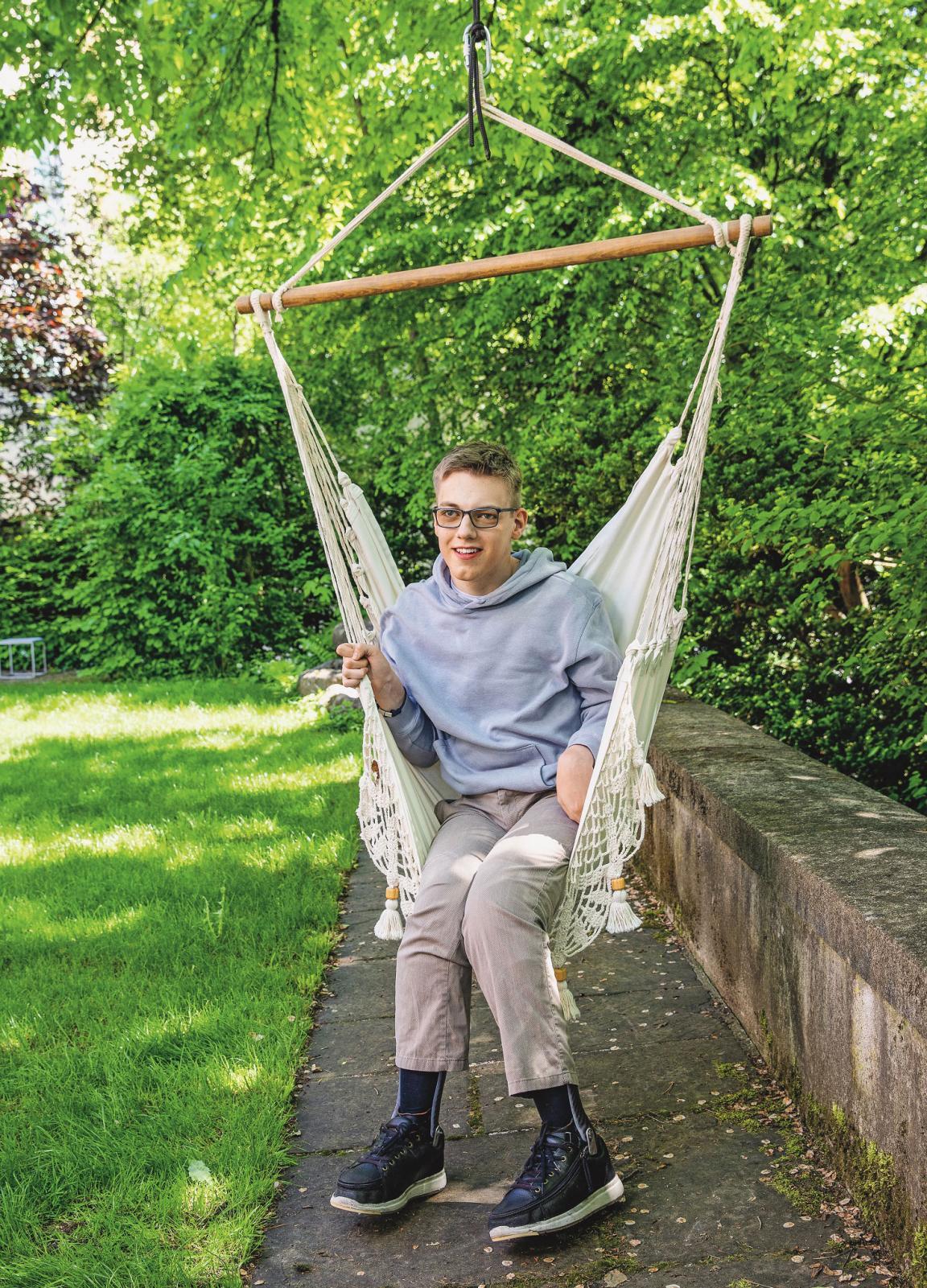 Marius Moser sitzt in einer Hängeschaukel in einem Garten.