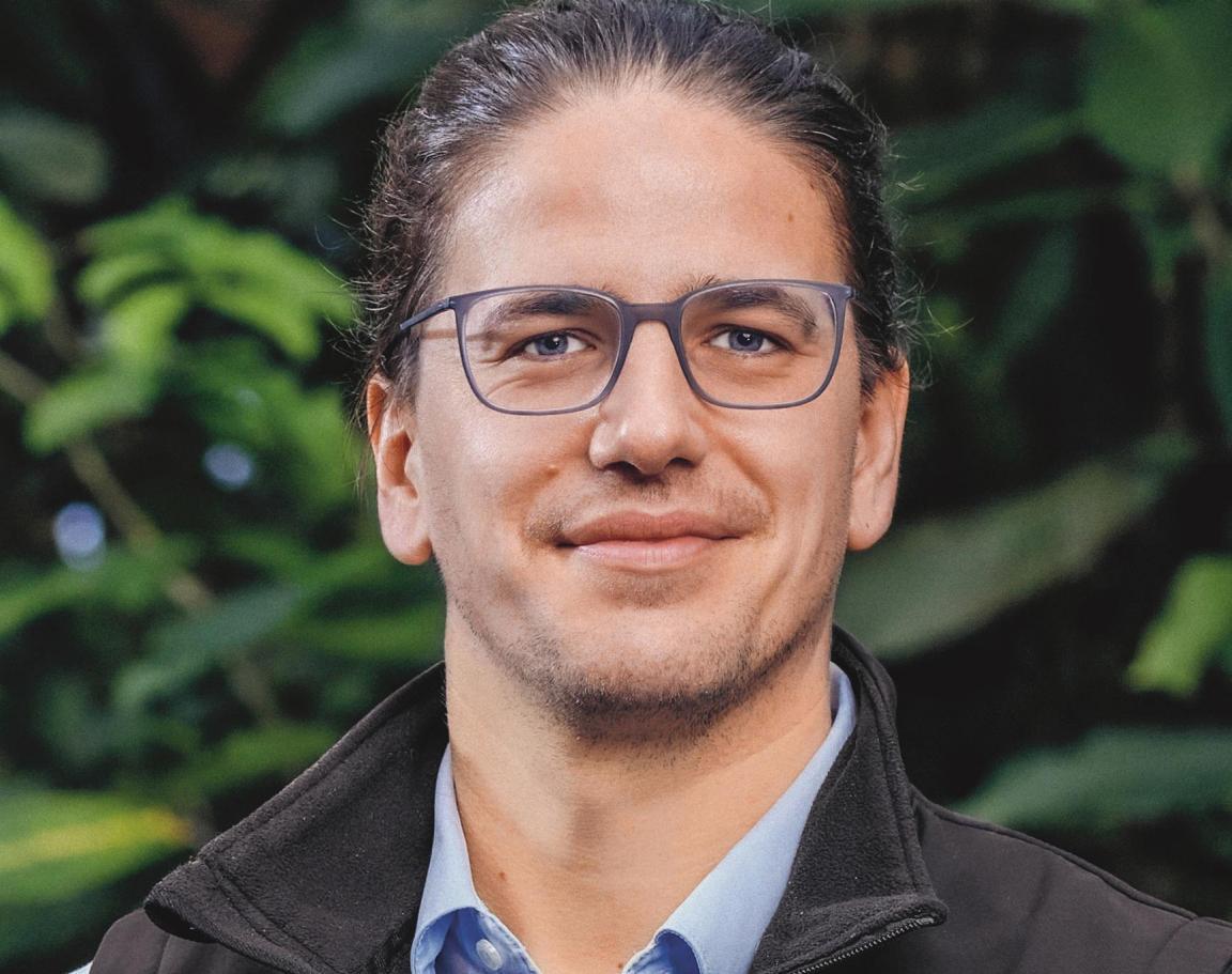 Zoodirektor im Portrait vor einem Hintergrund aus Blättern.