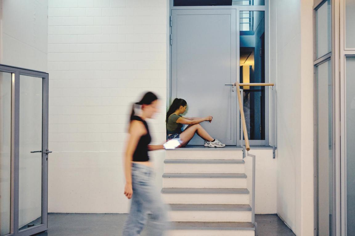 Jugendliche sitzt vor Türe auf Treppe