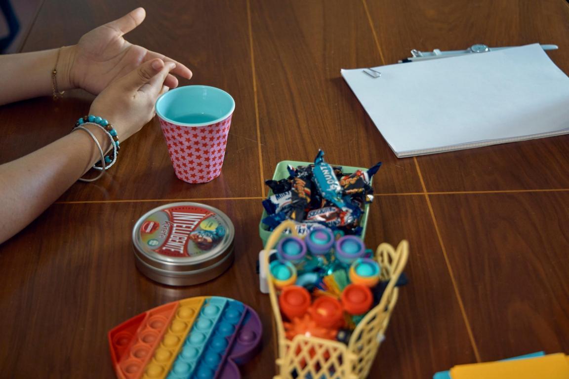 Hände auf Tisch gelegt, auf dem Süssigkeiten und farbige Fidgettoys liegen