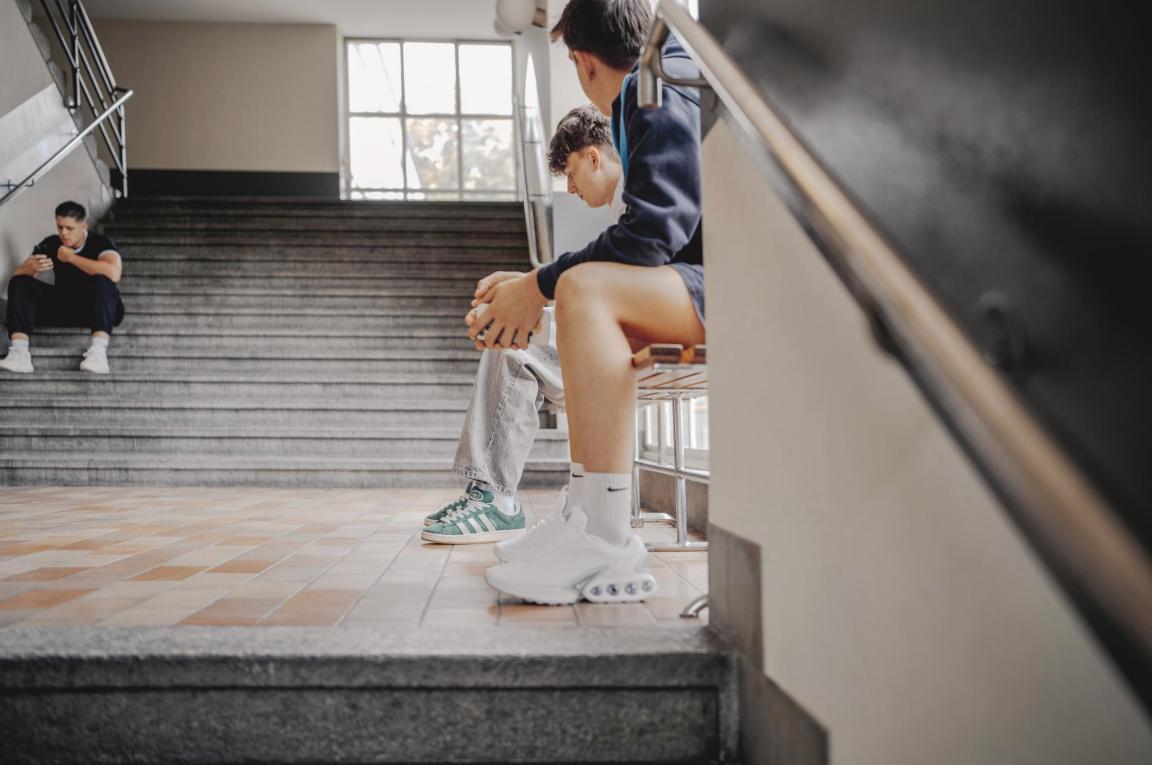 Drei Jugendlichesitzen im Treppenhaus einer Berufsfachschule