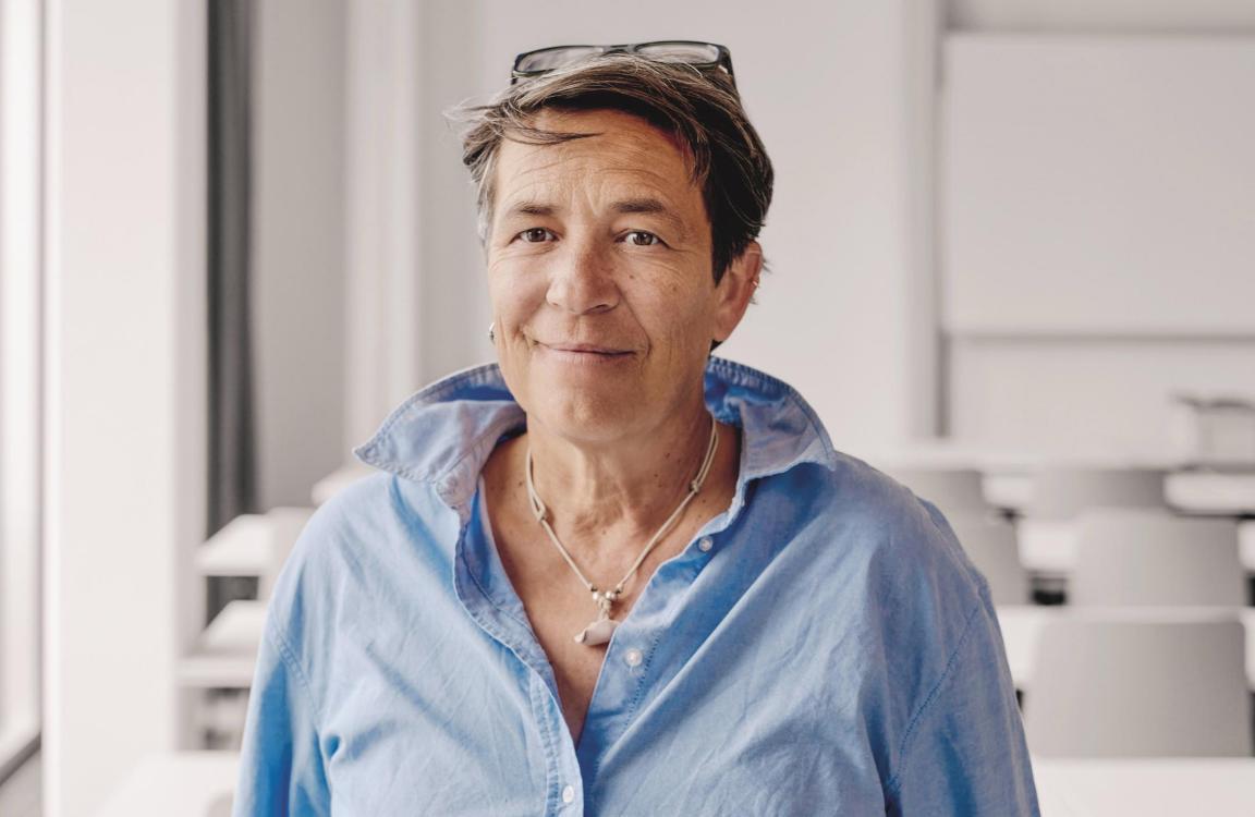 Frau mit blauem Hemd steht in einem Schulzimmer