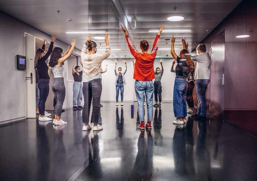 Angehende Lehrpersonen stehen im Kreis und heben die Arme im Gang der PHZH