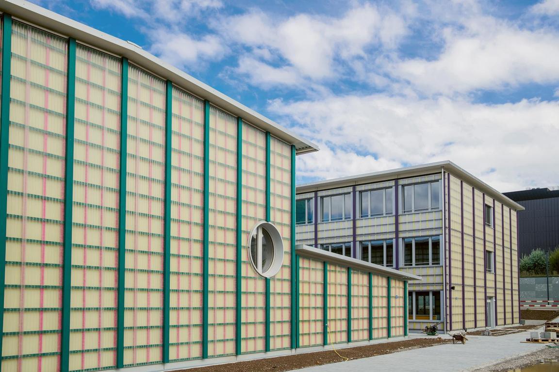 Gebäude mit grünen und pinken Latten und einem runden Fenster.