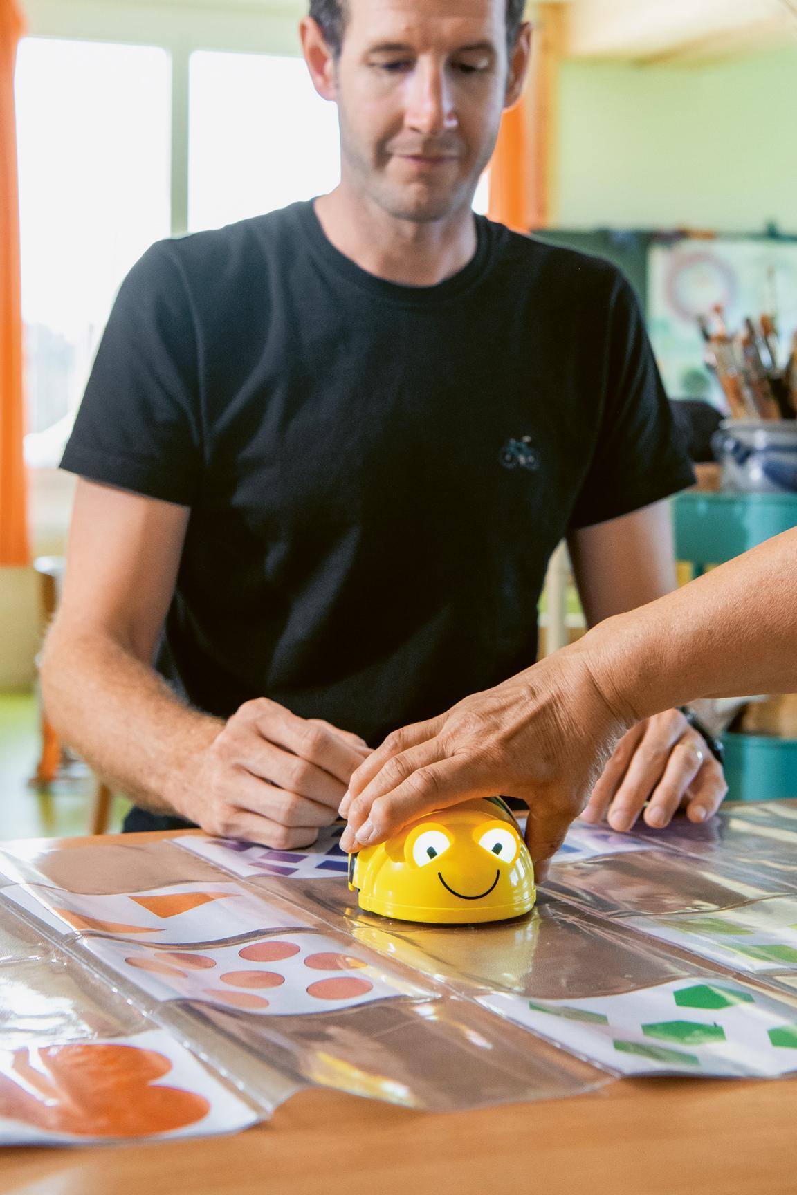 Eine Person sitzt vor einem gelben Roboterkäfer.