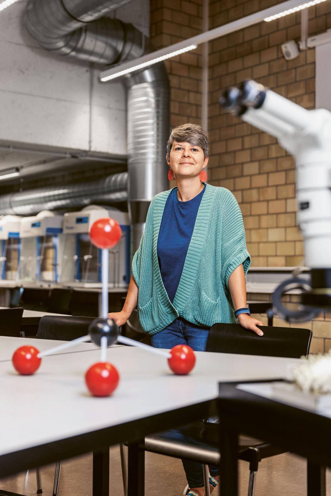 Biologin Morana Mihaljević steht in einem Labor am Campus Irchel. Im Vordergrund sind ein Mikroskop und ein Molekülmodell zu sehen.