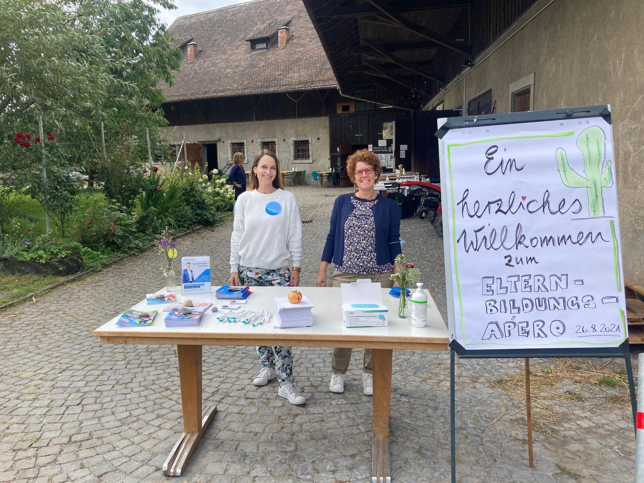 Zwei lächelnde Damen stehen am Empfangstisch