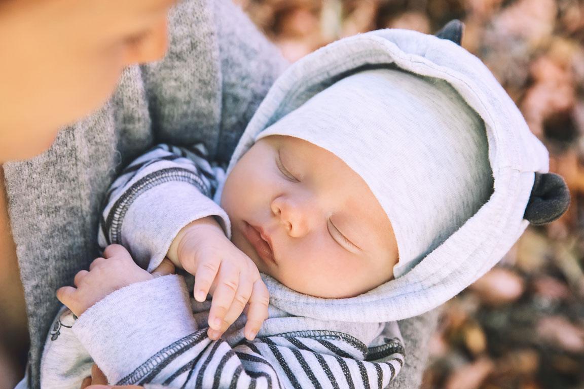 Schlafendes Neugeborenes in den Armen seiner Mutter.