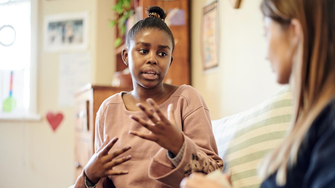 Eine Jugendliche erklärt ihre Situation im Gespräch mit einer Beraterin in einem vertraulichen Rahmen.