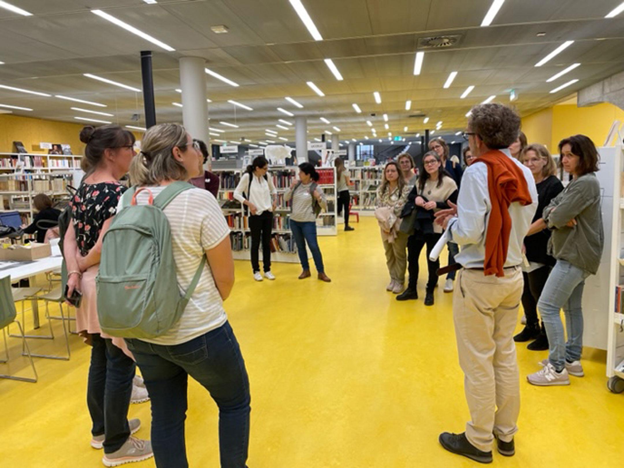 Teilnehmende des Bibliocamps 2022  hören in der Bibliothek dem Führer zu.