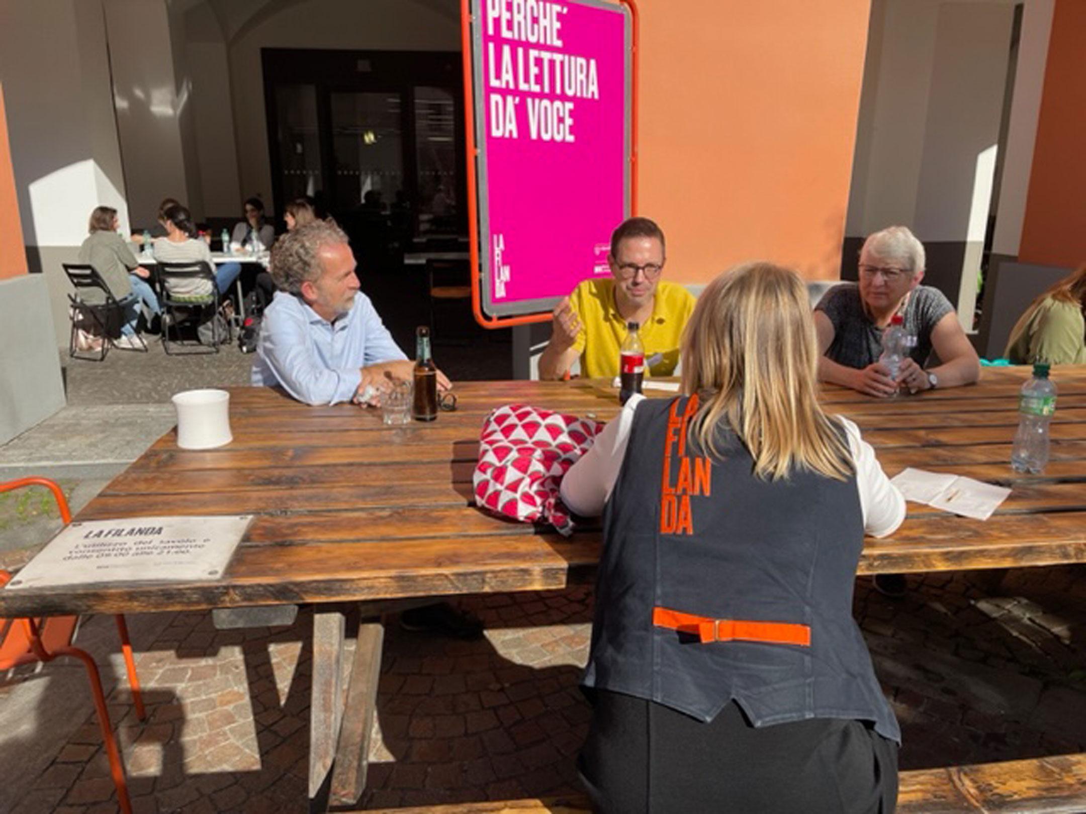 Teilnehmende des Bibliocamps 2022  sitzen in der Pause draussen an der Sonne.