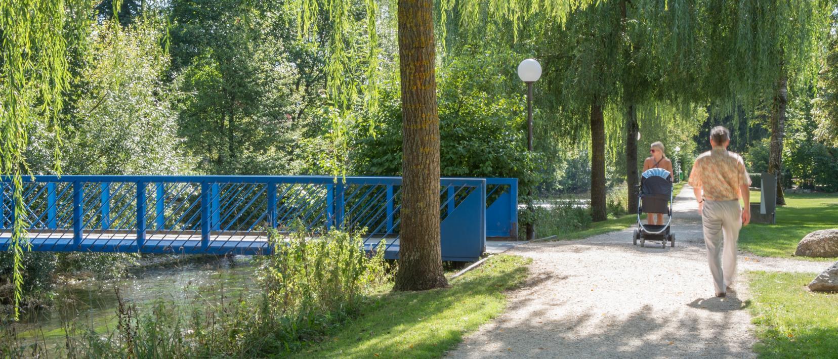 Eine Frau mit Kinderwagen und ein Spaziergänger kreuzen sich auf dem Glattuferweg.