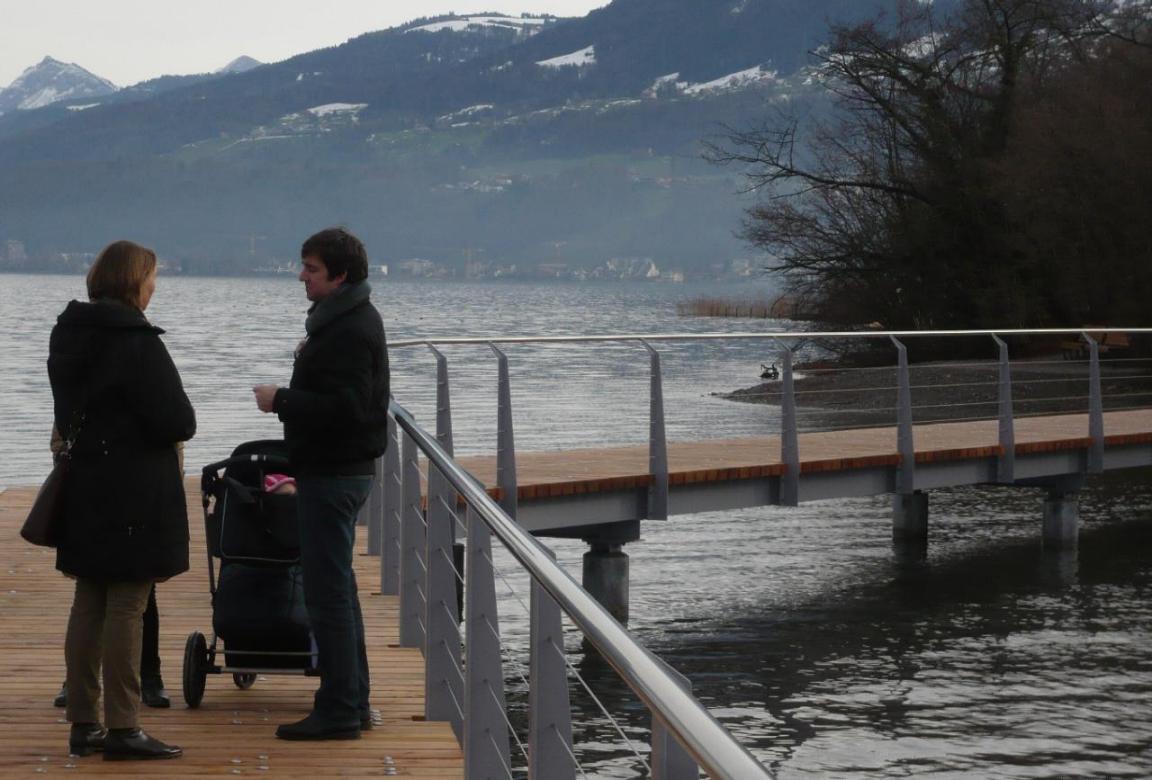Spaziergänger mit Kinderwagen unterhalten sich auf einem Steg des Seeuferwegs bei Richterswil.