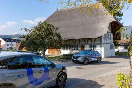 Zwei selbstfahrende Fahrzeuge kreuzen sich auf einer Landstrasse im zürcherischen Furttal vor dem Strohdachhaus im zürcherischen Hüttikon. 