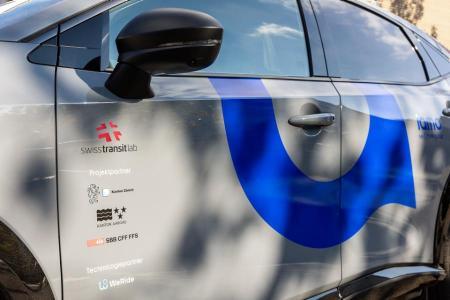 Seitliche Aufnahme des selbstfahrenden Fahrzeugs mit den Logos der Projektpartnern. 
