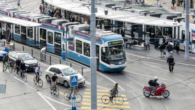 Das Bild zeigt das Central in der Stadt Zürich, mit Trams, Autos, Velos und Fussgängern.