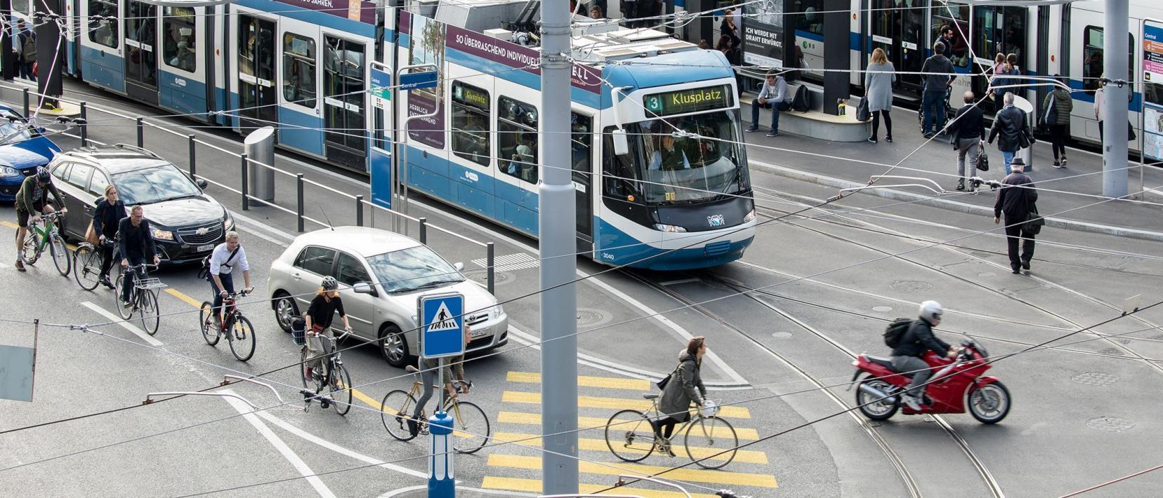 Das Bild zeigt das Central in der Stadt Zürich, mit Trams, Autos, Velos und Fussgängern.