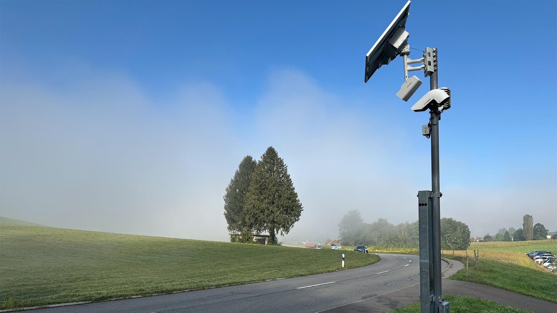 Frühwarnanlage mit Solarmodul an einer Landstrasse bei Nebel.
