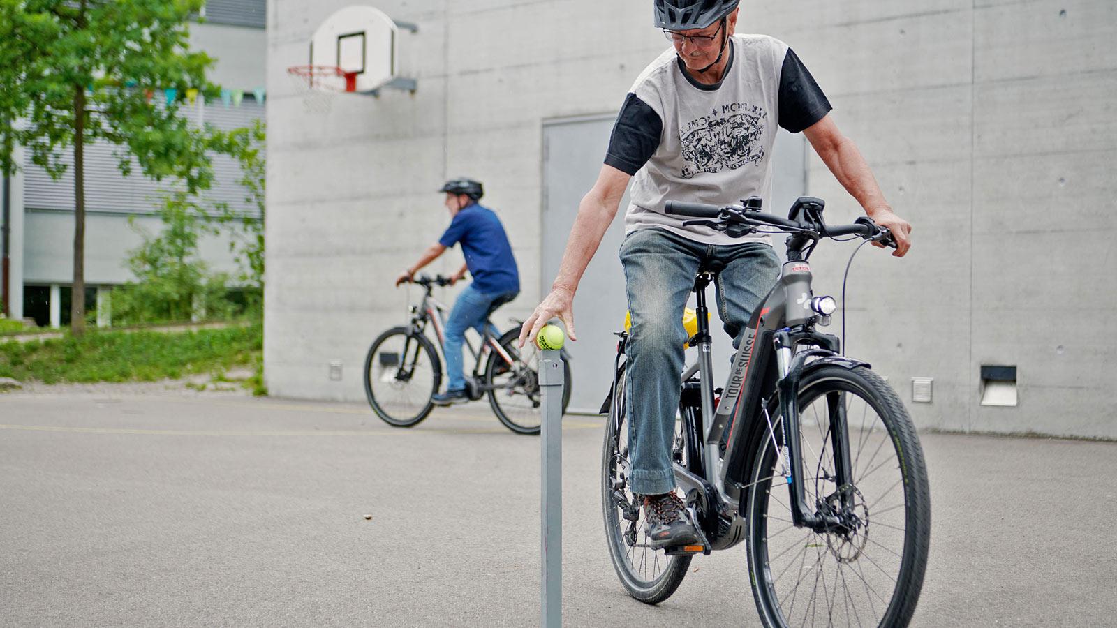 Ein Teilnehmer platziert während der Fahrt einen Tennisball auf eine Stange.