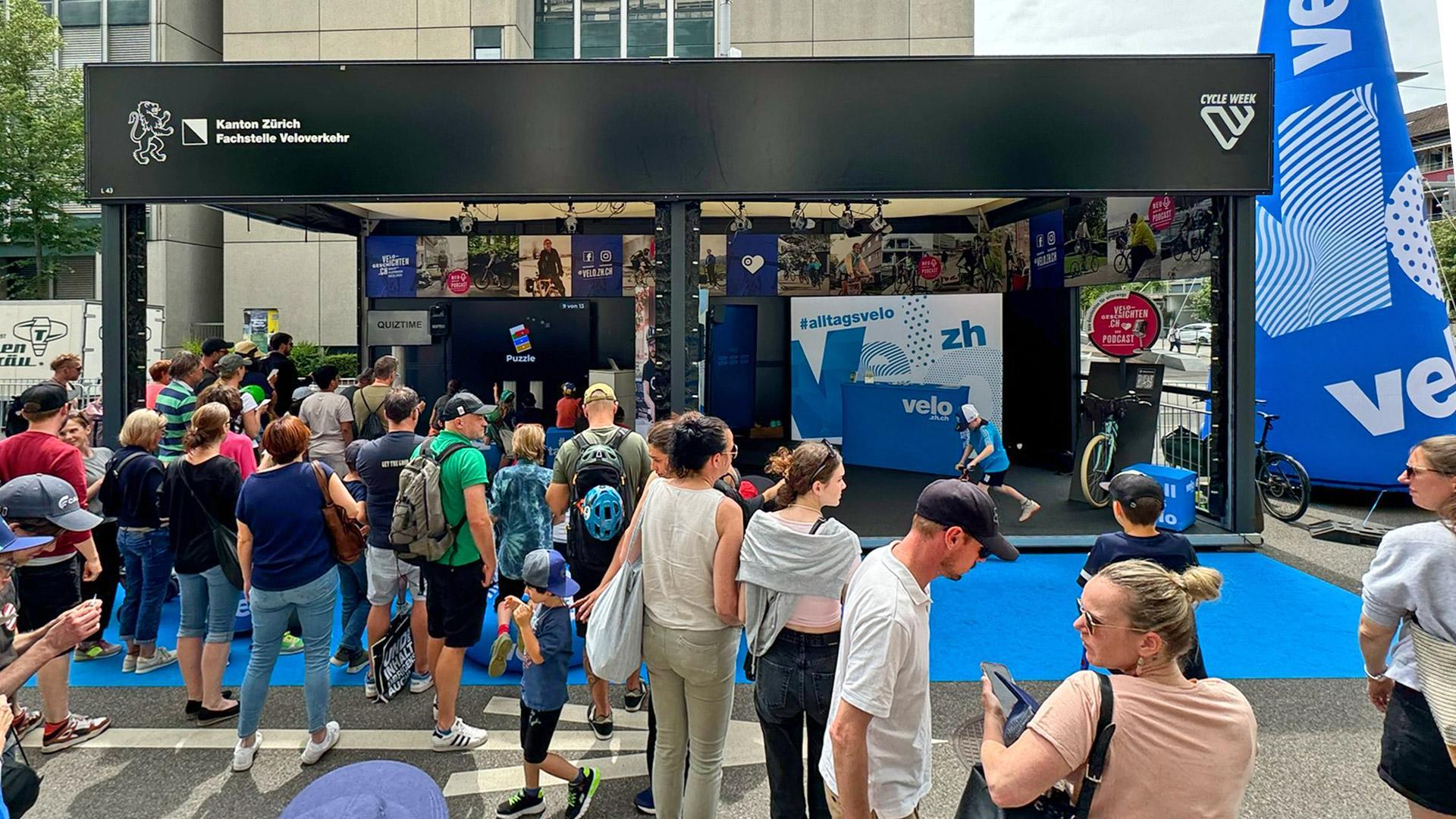 Stand der Fachstelle Veloverkehr Kanton Zürich auf der Cycle Week mit Besuchern und blauem Boden.