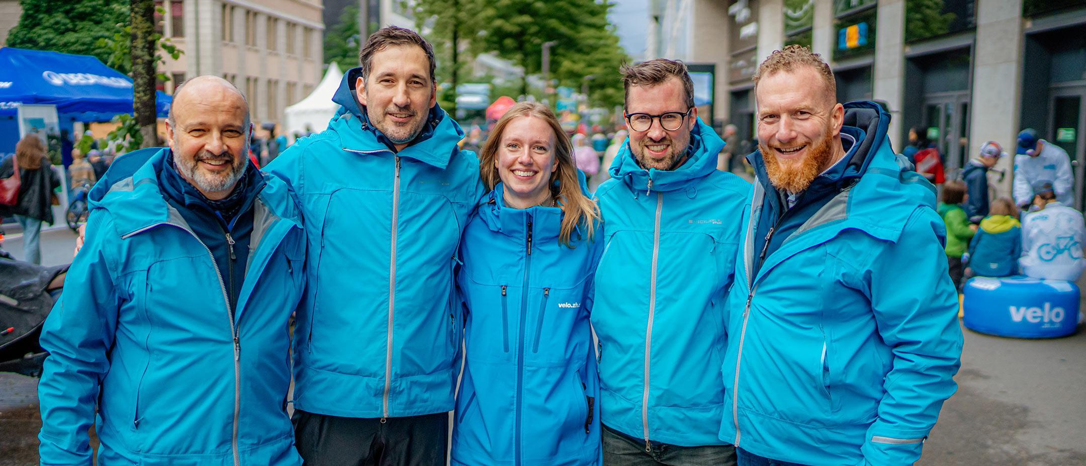 Das Team der Fachstelle Veloverkehr stelt sich für ein Teamfoto an der Cycle Week für den Fotografen auf. Die fünf Personen tragen Zürichblaue Jacken mit der Aufschrift «velo.zh.ch».
