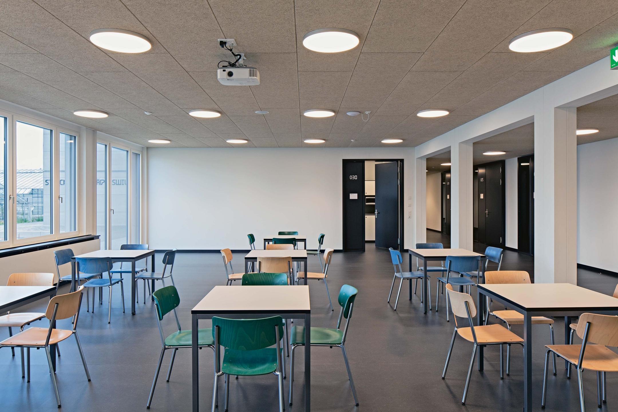 Aufenthaltsraum mit Tischen und den dazugehörigen Stühlen. 