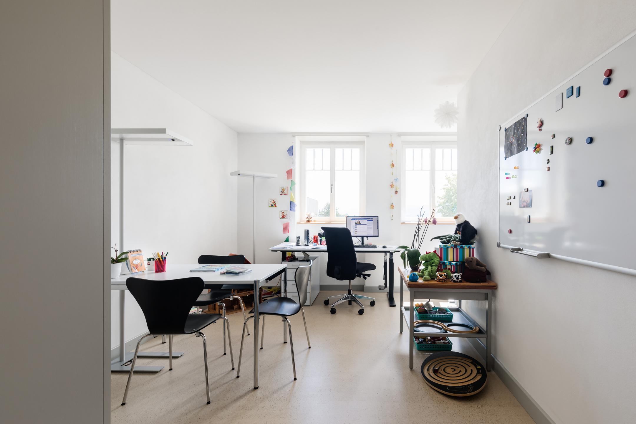 Wohnraum mit Arbeitstisch, Sideboard und Sitzgelegenheit.