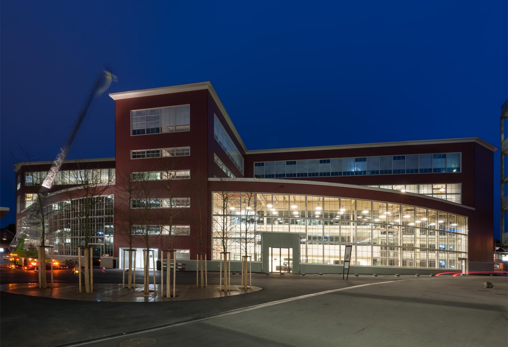 6-geschossiges Gebäude in der Abenddämmerung. Die Innenräume sind hell beleuchtet.