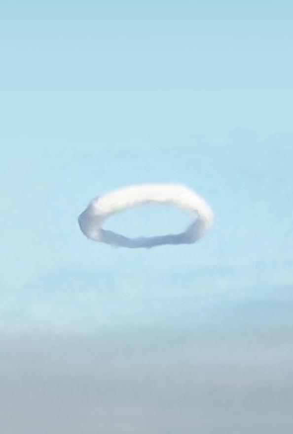 Das Bild zeigt einen Rauchring in der Luft. Ein Rauchring ist ein sichtbarer ringförmiger Wirbel, der zum Beispiel in der Natur durch Vulkane erzeugt wird.