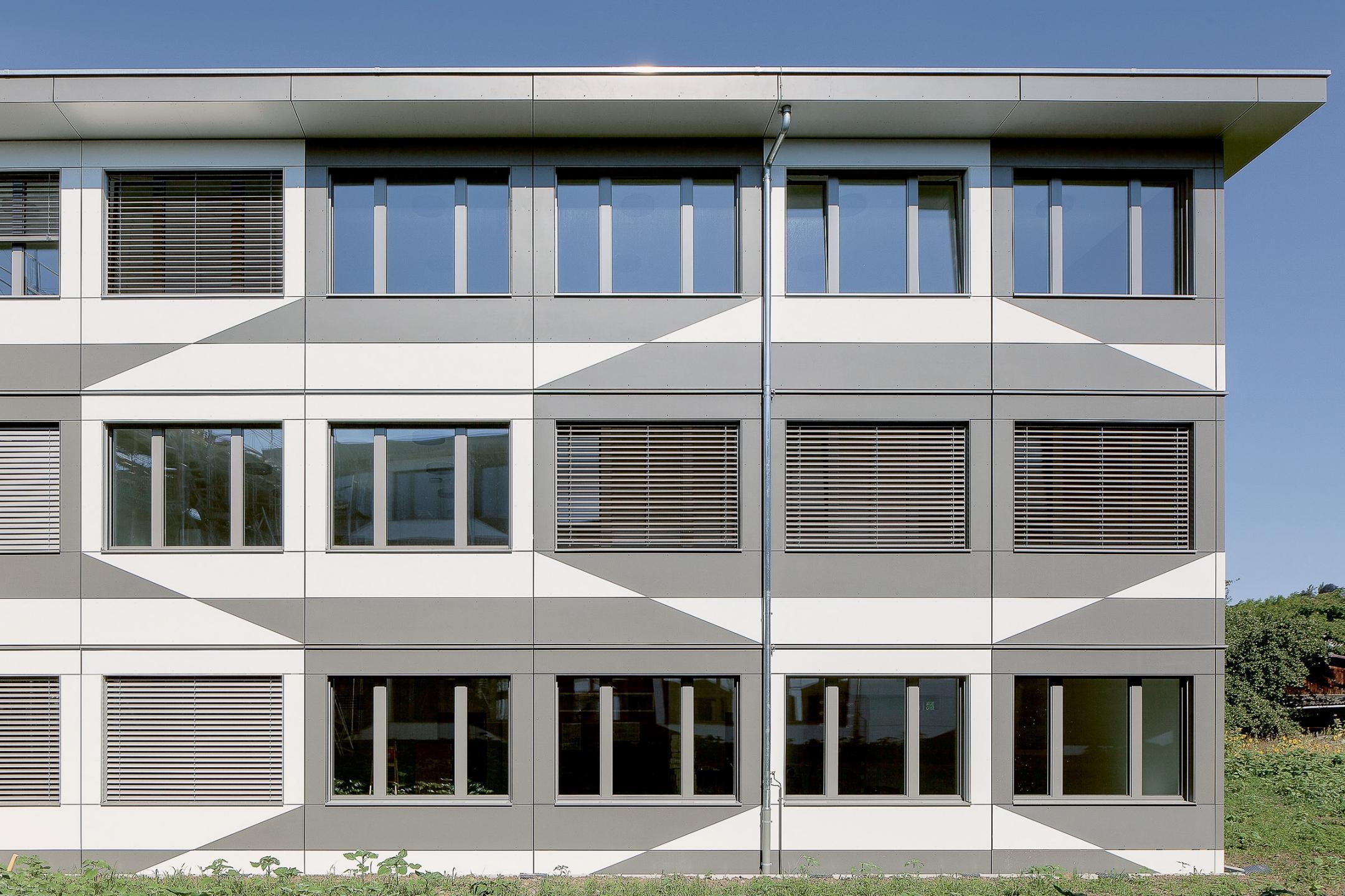 Frontalaufnahme eines Gebäudes, welches mit geometrischen, weissen- und grauen Vielecken bemalt ist.