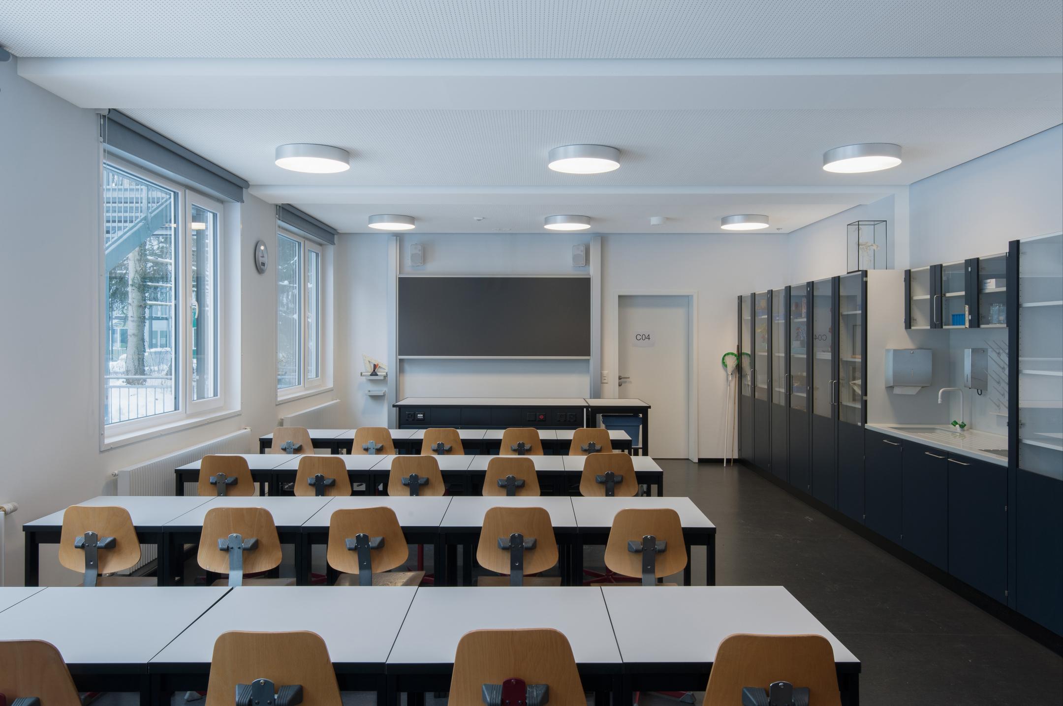 Innenansicht eines bestuhlten Klassenzimmers mit Wandtafel.