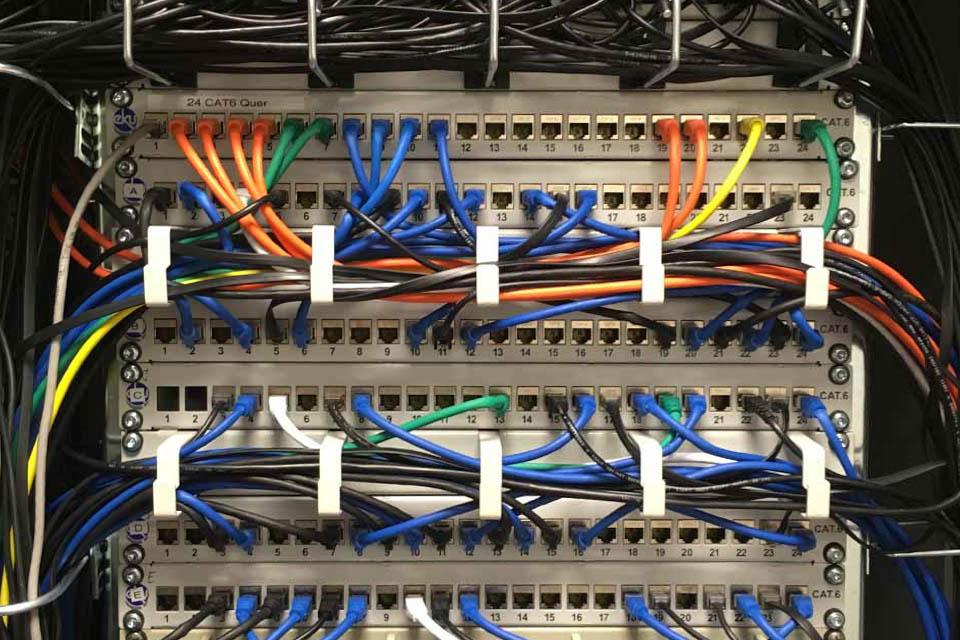 Fotografie eines UKV Racks mit vielen farbigen angeschlossenen Netzwerkkabeln..