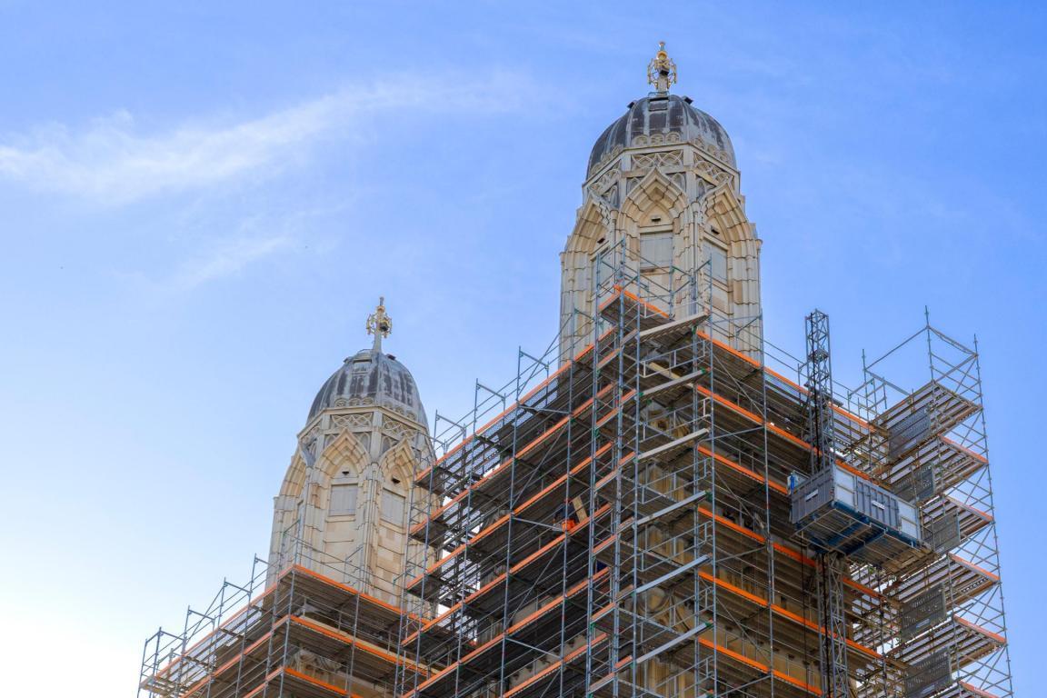 Zwei Kirchtürme, die bis fast oben von einem Baugerüst umgeben sind.