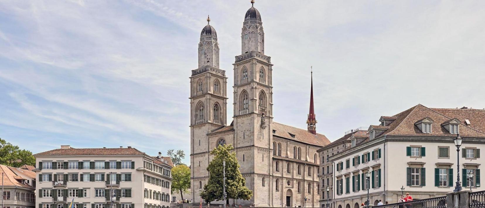 Kirche mit zwei Türmen mit einem Fluss und zwischen Häusern.