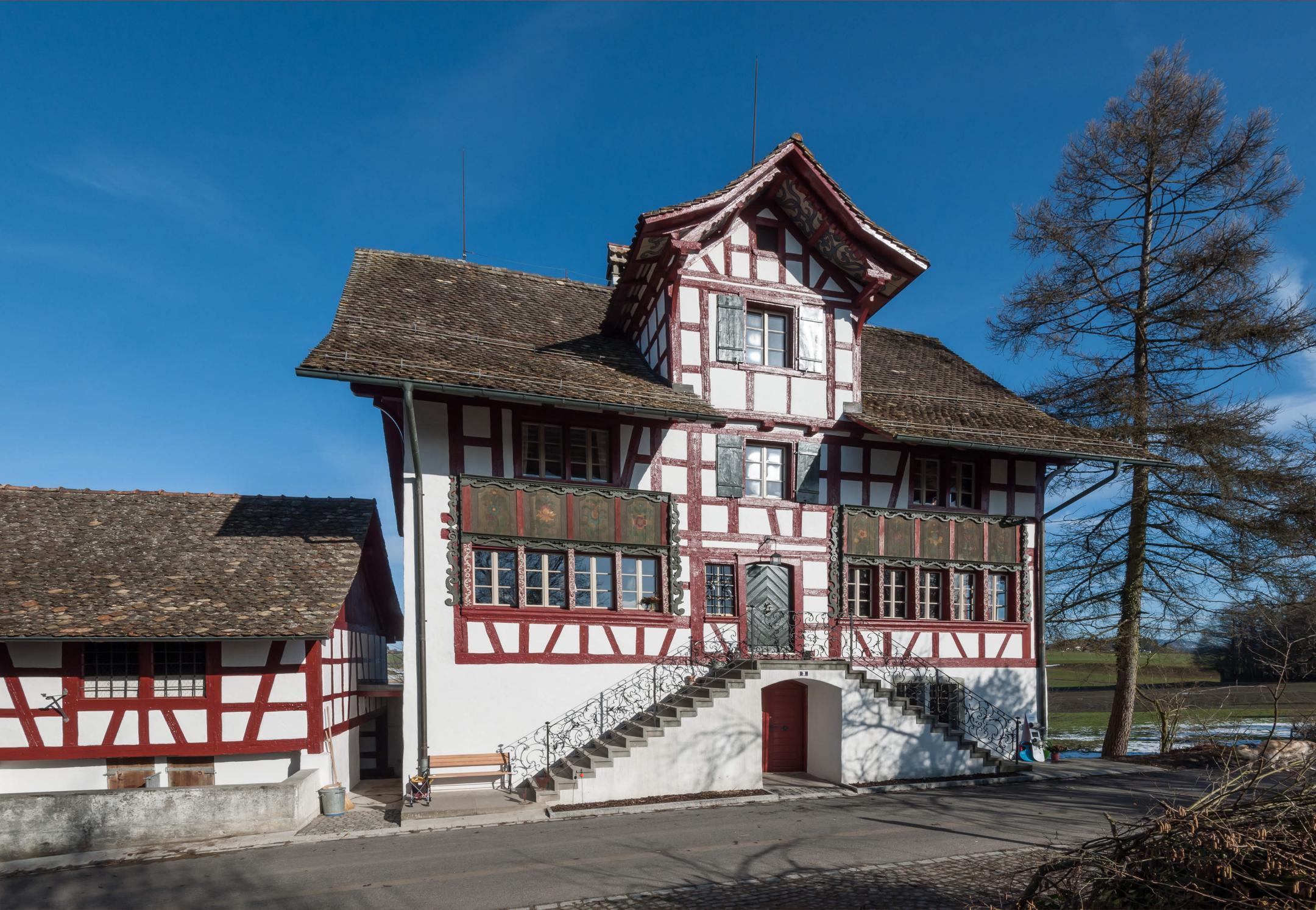 Gesamtansicht des alten Gebäudes vor blauem Himmel. Rechts vom Gebäude steht ein kahler Baum.
