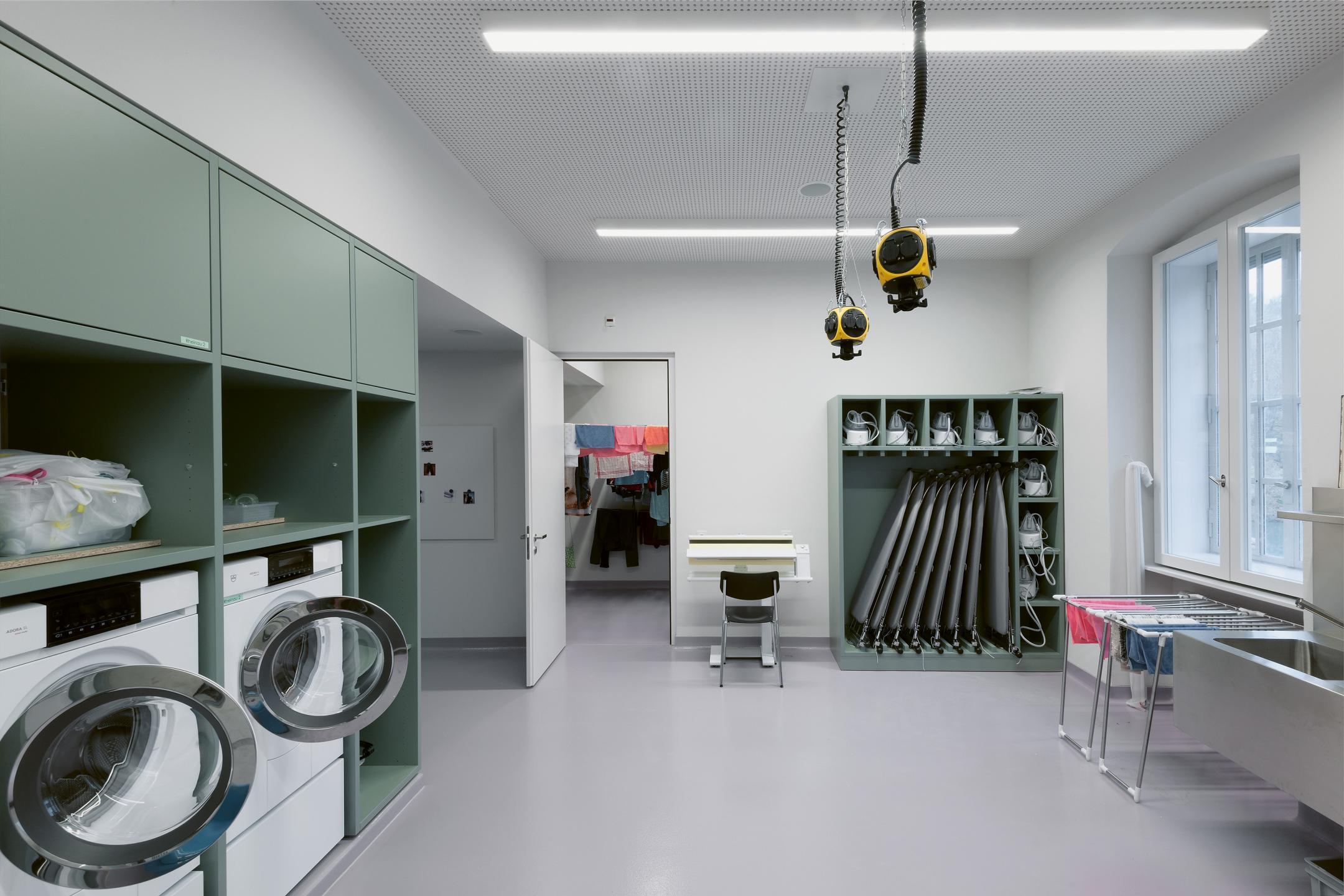 Hauswirtschaftsraum mit Bügelbrett und Waschmaschinen.