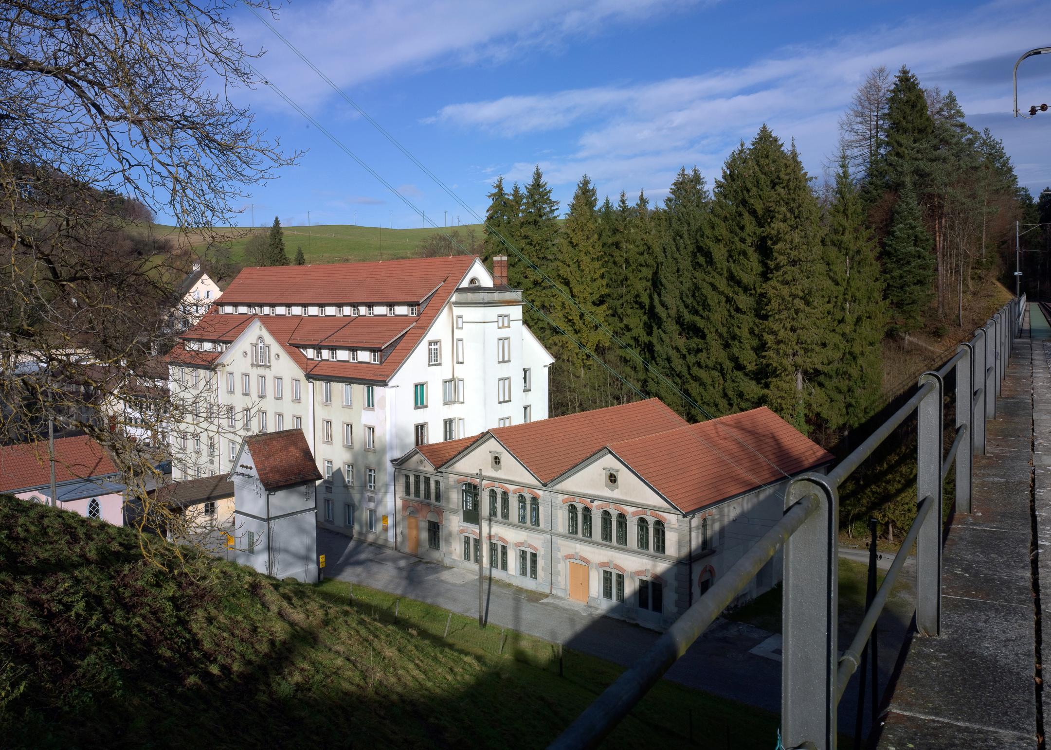 Mehrere Gebäude vor einem kleinen Wald von einer Brücke fotografiert.