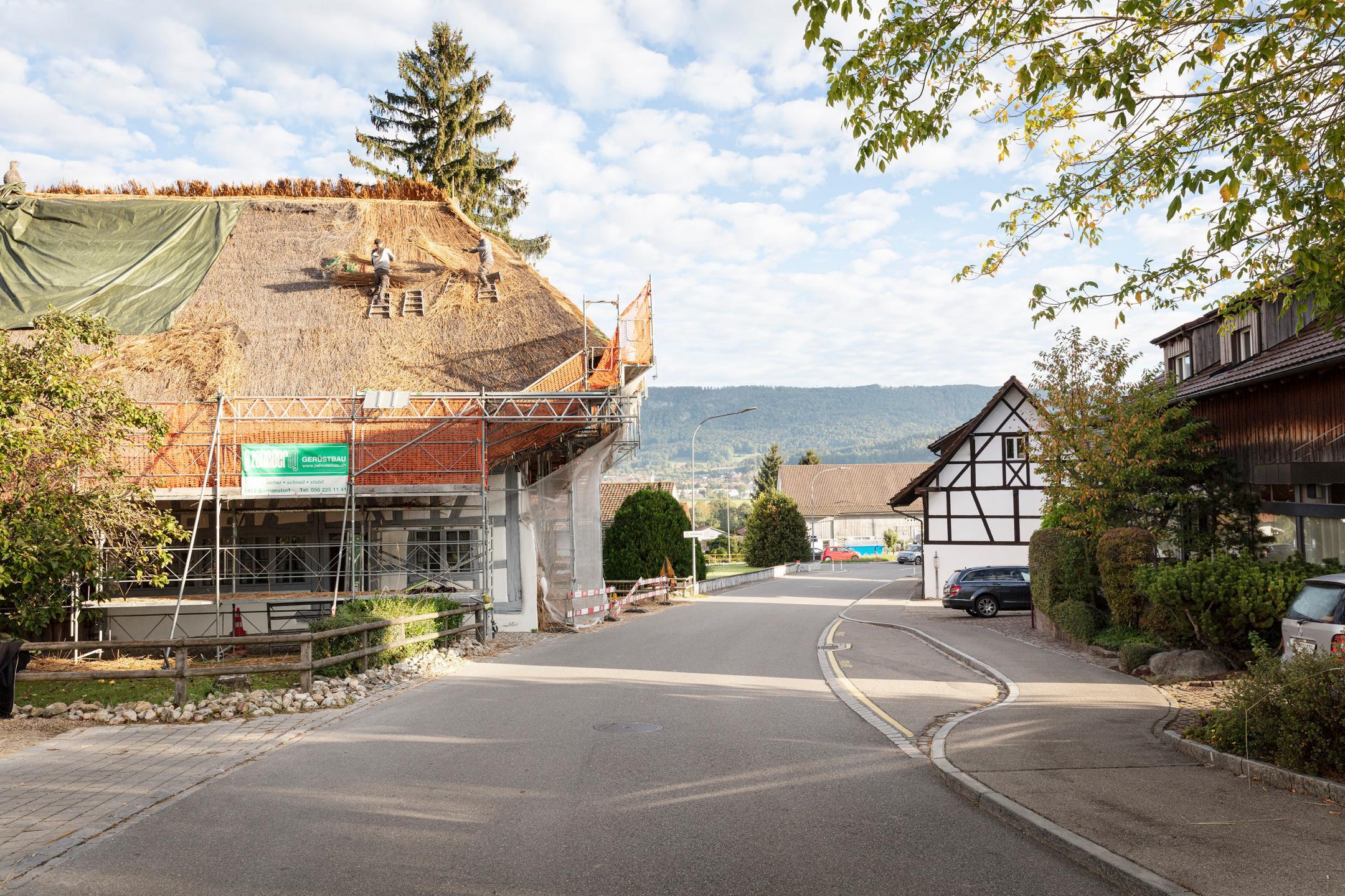 Die Südseite des Strohdaches wird abgedeckt, um später mit dem neuen Schilf wiedereingedeckt zu werden.