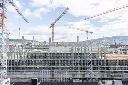 Die PJZ-Baustelle im August 2018, aus der Ferne aufgenommen. Mehrere Kräne und im Hintergrund die Stadt Zürich. 