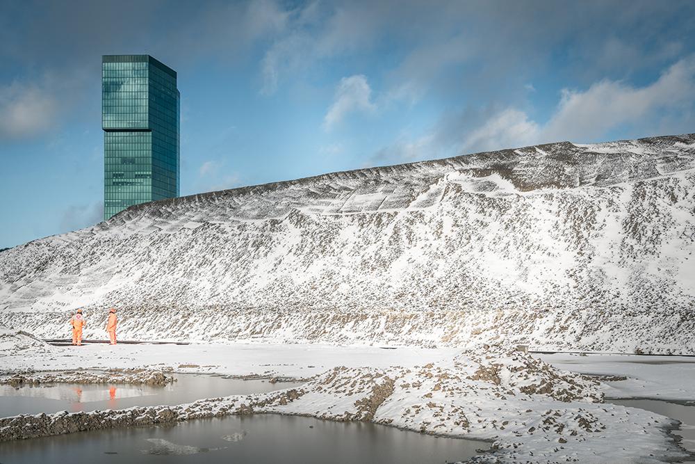 Eine verschneite Aufschüttung auf der PJZ-Baustelle im Januar 2018. Drei Arbeiter stehen davor, im Hintergrund der Prime Tower. 