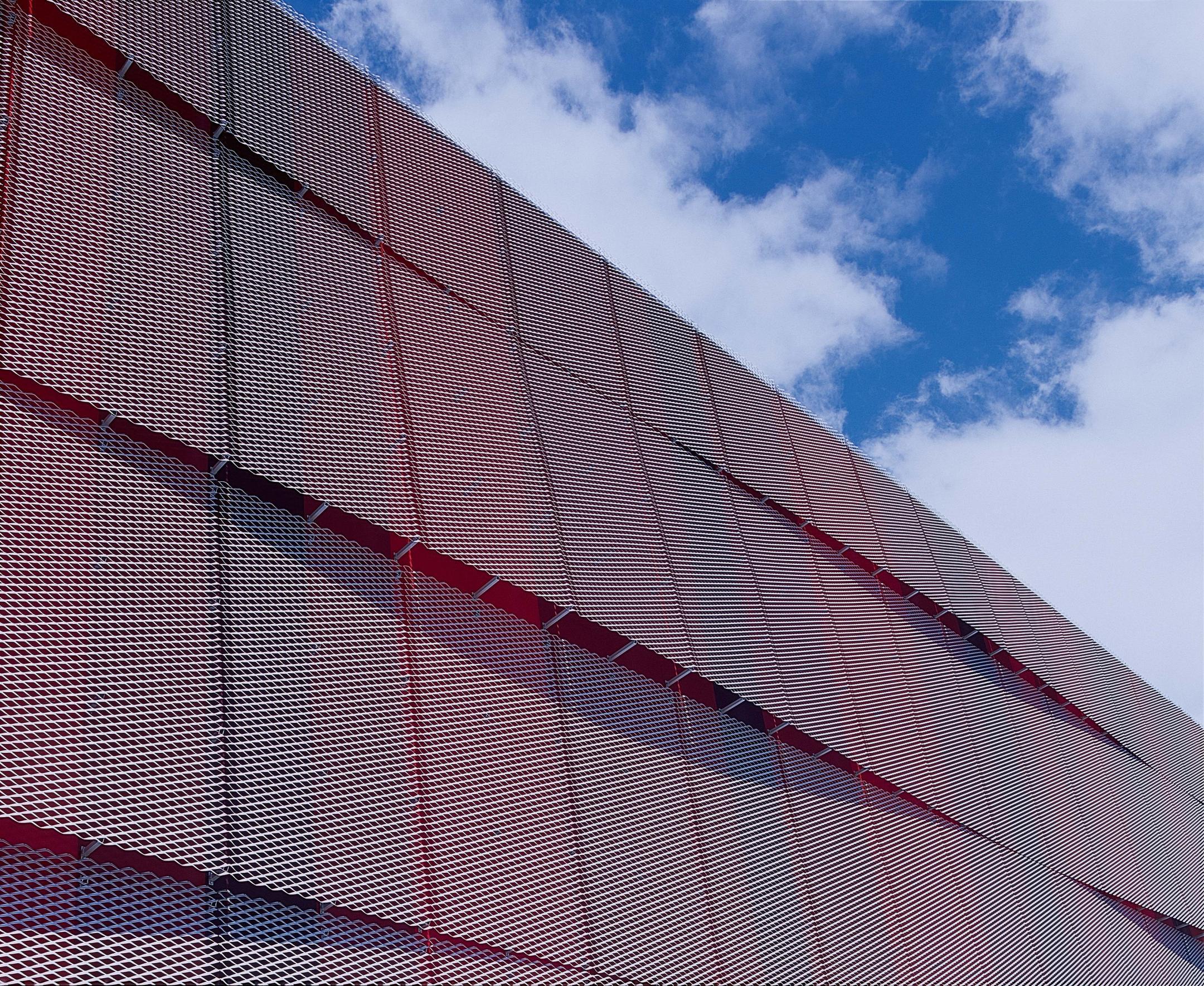 Spielerische rötliche Fassade in einer Wellenartigen Form. Keine Fenster.