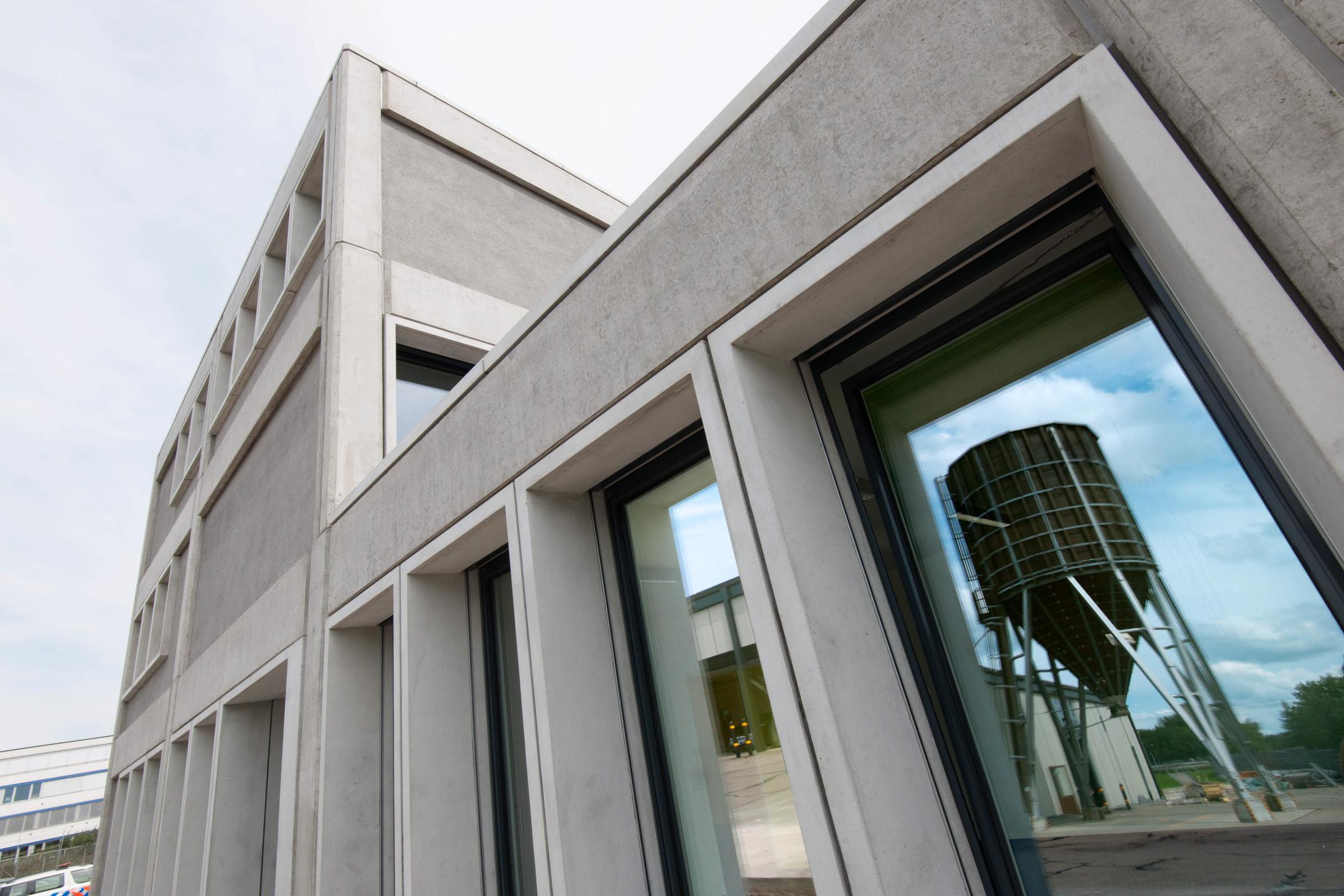 Durch die extreme Perspektive verzogene Betonfassade. Im grossen Fenster spiegelt sich ein Salzsilo.